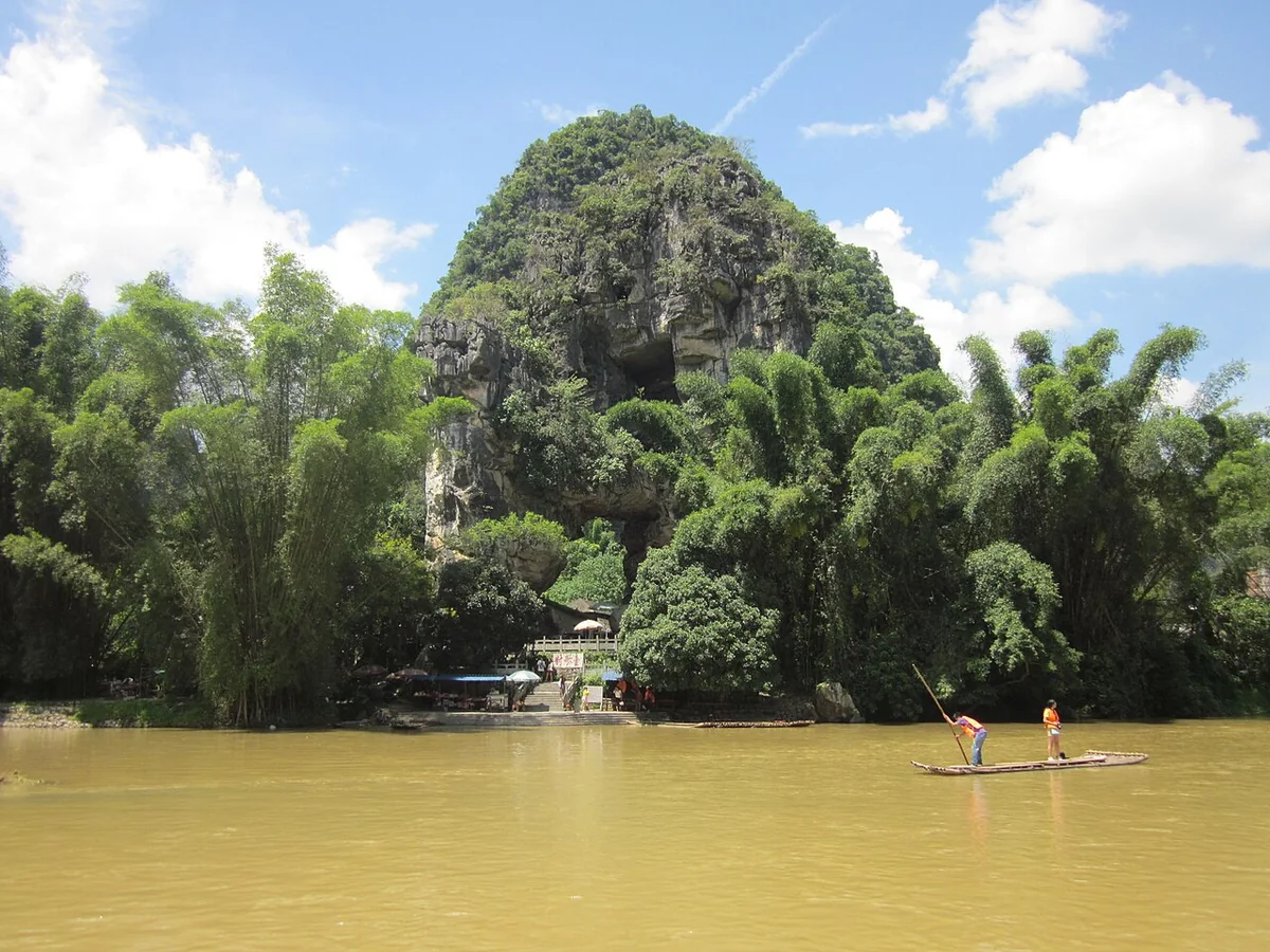 A bamboo raft passes a green limestone hill along the Li River in Yangshuo County, Guilin.